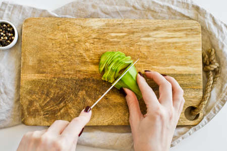 The chef peels avocado on a wooden chopping Board. White background, top view