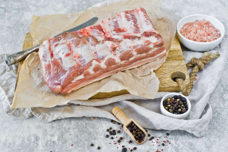 Raw pork ribs on a wooden chopping Board. Gray background, side view, space for textの写真素材