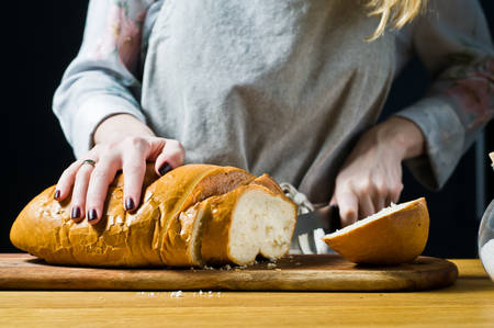 Chef cuts bread. The concept of cooking French toast. Black background, side view, space for text,...