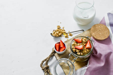 Muesli with strawberries in a glass jar. White background, side view, space for text. Healthy vegan snackの写真素材