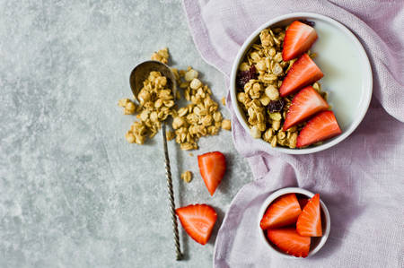 Breakfast with granola, strawberries and yogurt. Gray background, top view, space for textの写真素材