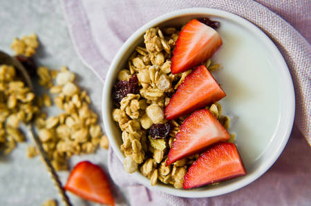 Muesli bowl with granola, strawberries and yogurt. Grey background, top view, close up