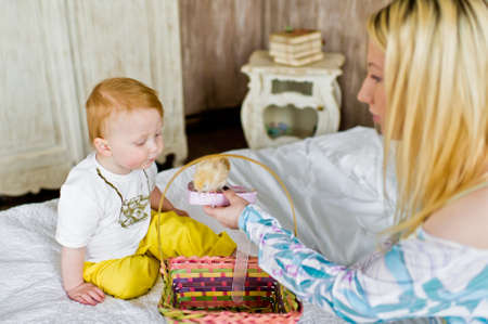 Mom holds a box with a live chicken and shows it to the child