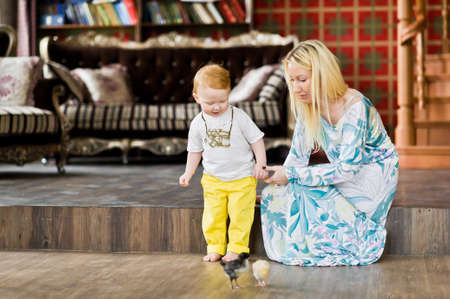Mom and son sit on the floor and look at the chickens