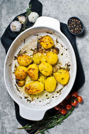 Baked potatoes in a baking dish. Grey background, top viewの写真素材