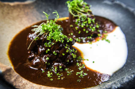 Baked lamb with sauce and herbs, dark background, top viewの写真素材