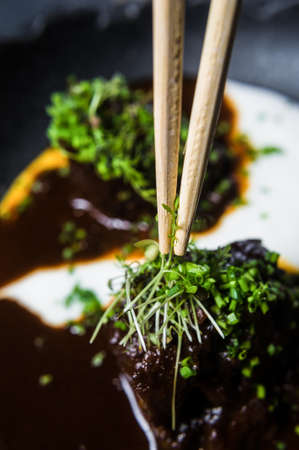 Baked lamb with sauce and herbs, dark background, top view
