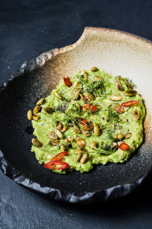 guacamole with roasted peanuts, black background, top viewの写真素材