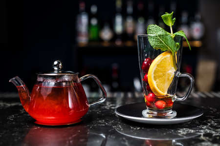 fruit tea with cranberries, teapot and glass, dark backgroundの写真素材