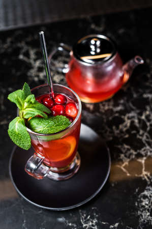 fruit tea with cranberries, teapot and glass, dark backgroundの写真素材