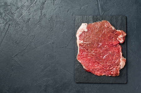 Beef flank steak on a stone Board. Black background, top view, space for textの写真素材