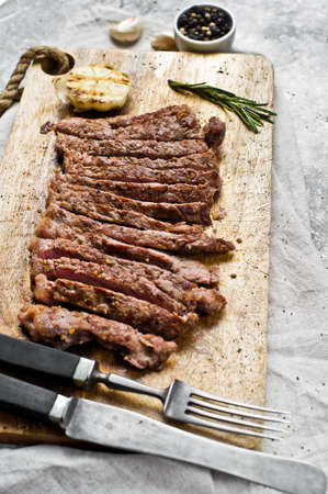 Flank steak on a wooden chopping Board. Gray background, top view, space for text