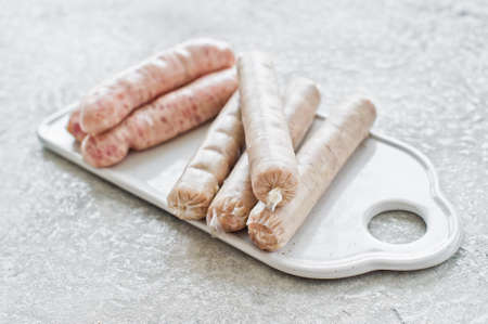 Assorted sausages on a ceramic cutting Board, pork, Turkey, chicken. Gray background, side viewの写真素材