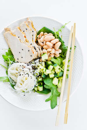 Buddha bowl with glass noodles, beans, chicken breast, spinach, arugula and cucumber. White...