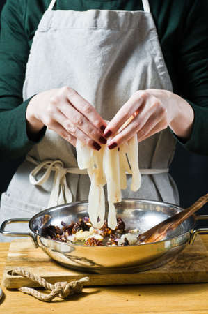 Chef puts squid in the pan. Black background, side view, kitchen