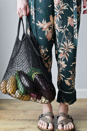 Girl holding eco cotton bag with vegetables. zero waste,  shopping concept. plastic free. potatoes, eggplant, squash, broccoli, cabbageの写真素材