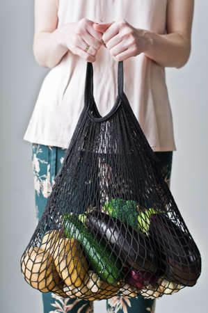 Girl holding eco cotton bag with vegetables. zero waste,  shopping concept. plastic free. potatoes, eggplant, squash, broccoli, cabbageの写真素材