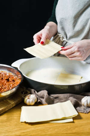 Chef hands making a lasagna. Side view, space for text.の写真素材
