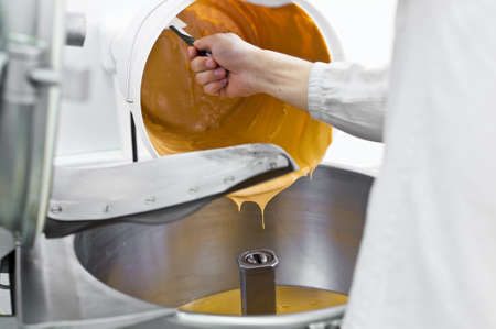 worker fills peanut butter in industrial mixer, food industry, conveyor line