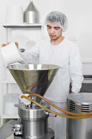 30.03.2019 Russia, Saint-Petersburg - worker putting in coconut chips in an Industrial crusher - press. Production of coconut oil, paste.のeditorial素材