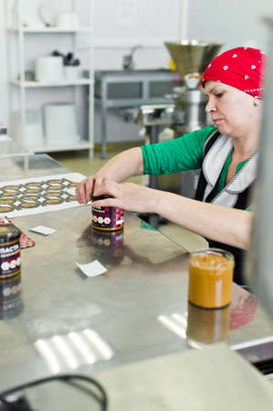 30.03.2019 Russia, St. Petersburg - worker labels on cans of peanut butter, food industry, conveyor...