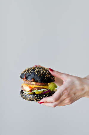 Hands holding a juicy Burger. Side view, gray background, space for textの写真素材