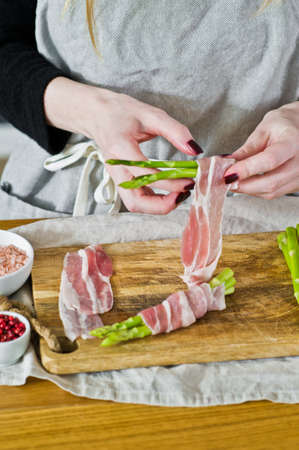 The chef prepares mini asparagus in bacon. Side view, the background of the kitchen, concept of cooking food balanced dietの写真素材