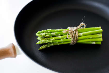 Mini asparagus in a pan. White background, top view, space for textの写真素材