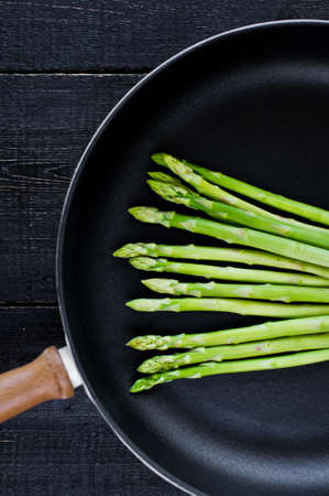 Green asparagus in the pan. Black background, top view, space for textの写真素材