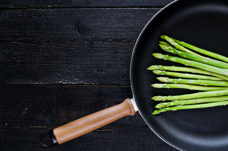 Green asparagus in the pan. Black background, top view, space for textの写真素材