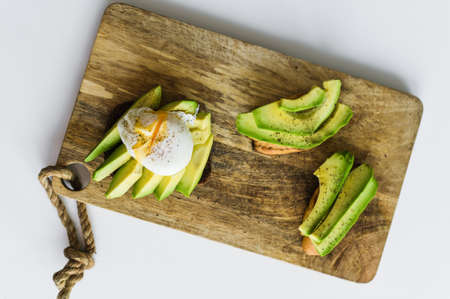 Toast, avacado sandwich and poached egg on a wooden chopping Board