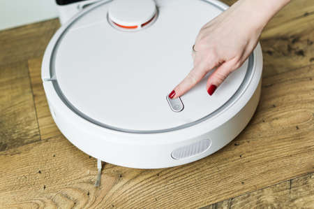 The girl hand switch on a robot vacuum cleaner