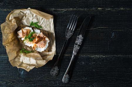 Sandwich with smoked salmon fillet on black bread with soft cheese.の写真素材
