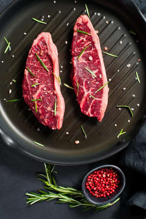 Beef ramp steak on the grill pan. Black background, top view
