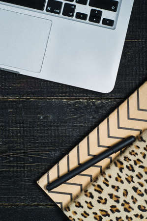 Flat lay home office desk. Female workspace with laptop,  golden accessories, diary on black...