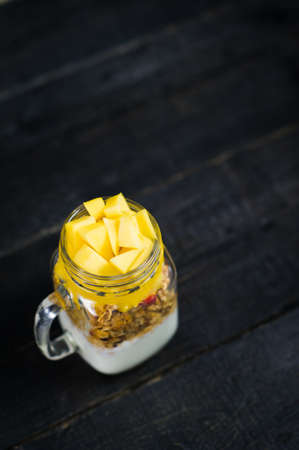 Healthy breakfast muesli and yogurt with mango smoothie in glass mason jarsの写真素材