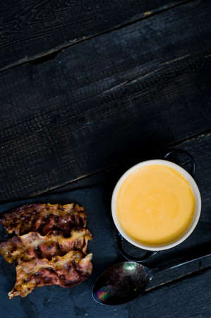 Pumpkin puree soup with fried bacon on black backgroundの写真素材