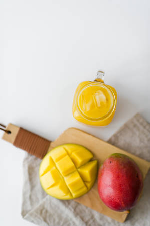 Ripe mango and a glass of mango juice on a wooden chopping Boardの写真素材
