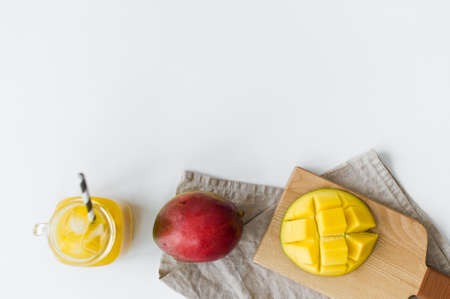 Ripe mango, half mango and a glass of mango juice on a wooden chopping Boardの写真素材