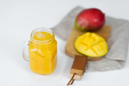 Ripe mango and a glass of mango juice on a wooden chopping Board