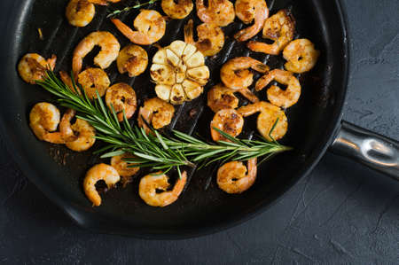 Close-up of a frying pan with fried king prawns and sprigs of rosemary and thymeの写真素材