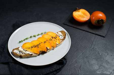 Sandwich with persimmon and soft cheese on a black backgroundの写真素材