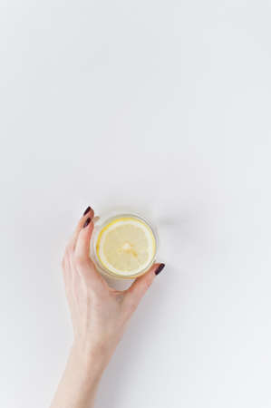 hands holding a glass of clear water with lemonの写真素材