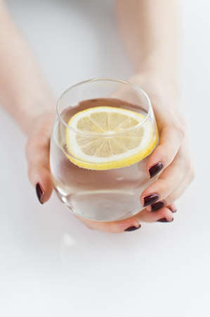 hands holding a glass of clear water with lemonの写真素材