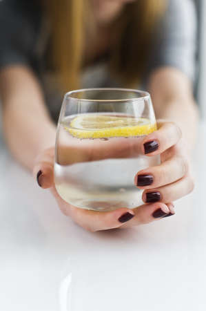 hands holding a glass of clear water with lemonの写真素材