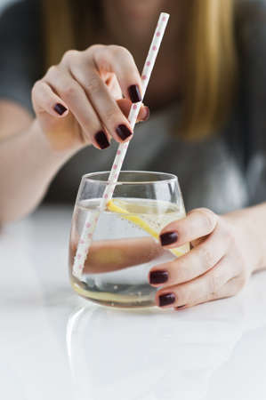 hands holding a glass of clear water with lemonの写真素材