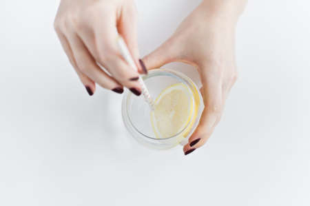 hands holding a glass of clear water with lemonの写真素材