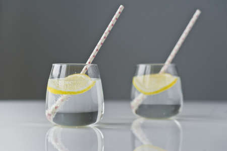 glass of clear water with lemon and straw
