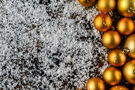 Beautiful christmas and new year golden deco baubles with white snowflakes on dark black background. Flat lay design. Copy Space.の写真素材