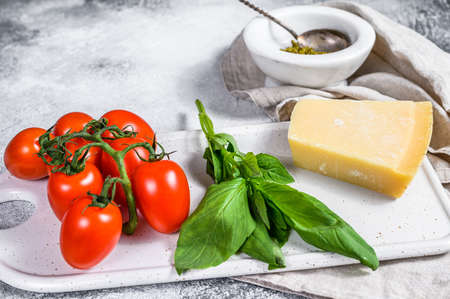 Homemade Pesto in marble mortar, Basil leaves and Parmesan on a chopping Board. Space for text.